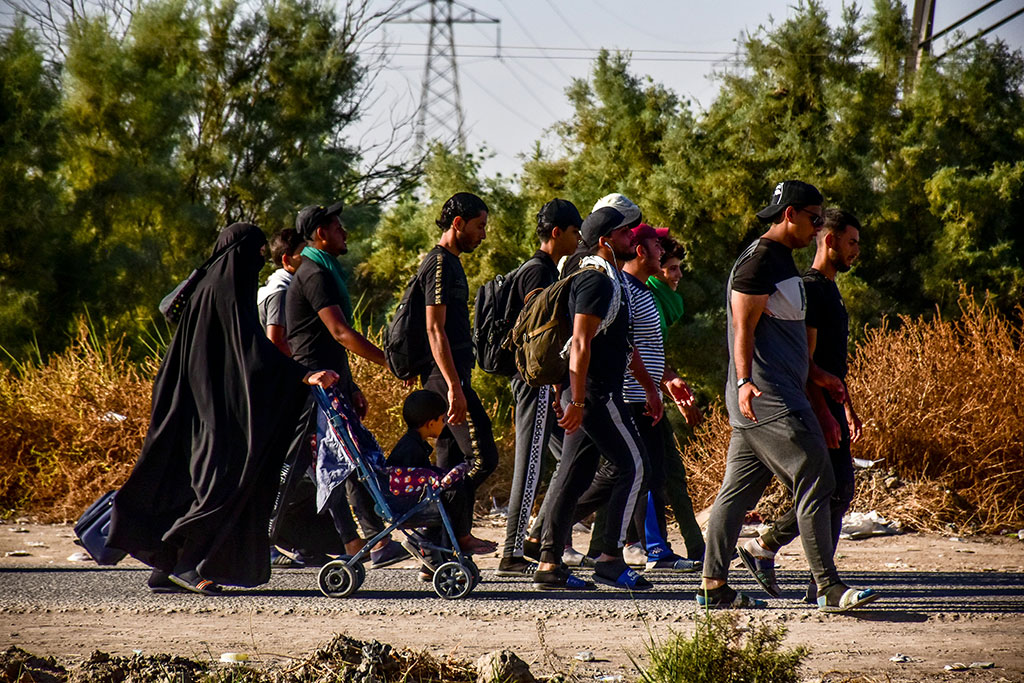 A family of pilgrims walk together along a road.