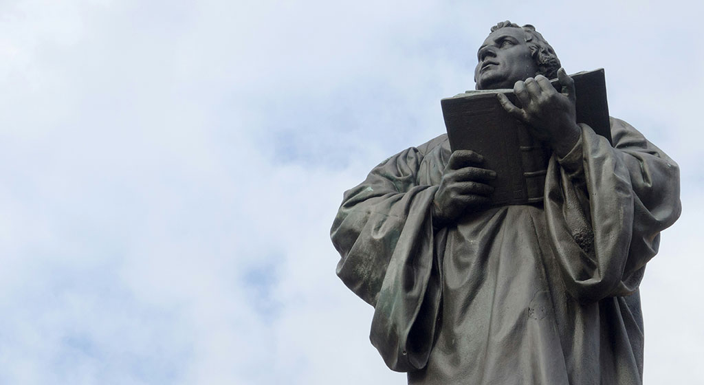 Looking up at a statue of Martin Luther holding an open bible.