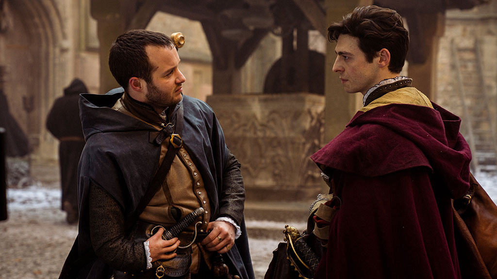 Two men in Tudor clothing converse in a street