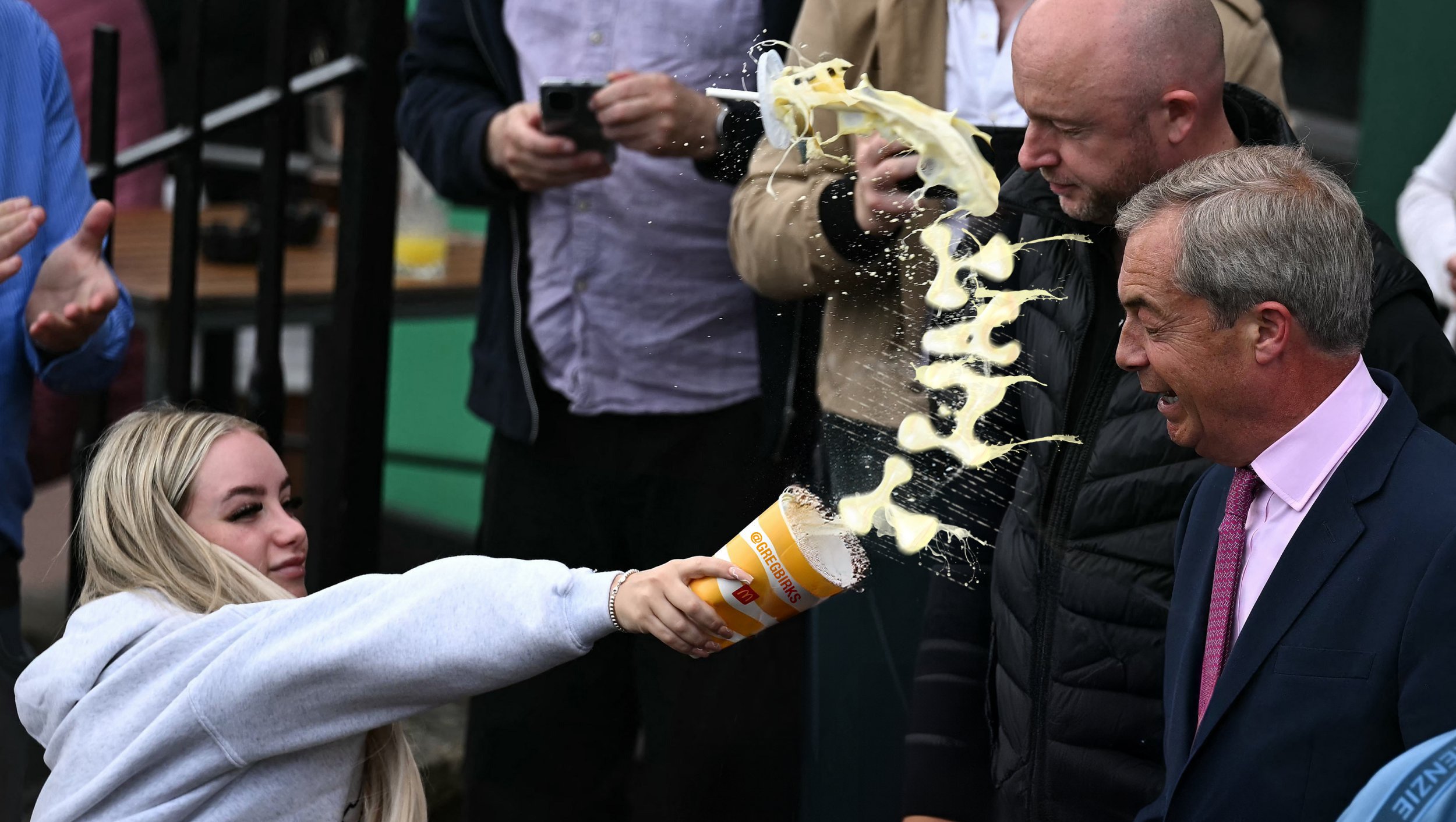 A woman throws a milkshake at a politician, the milk is mid-flight in a curved shape.