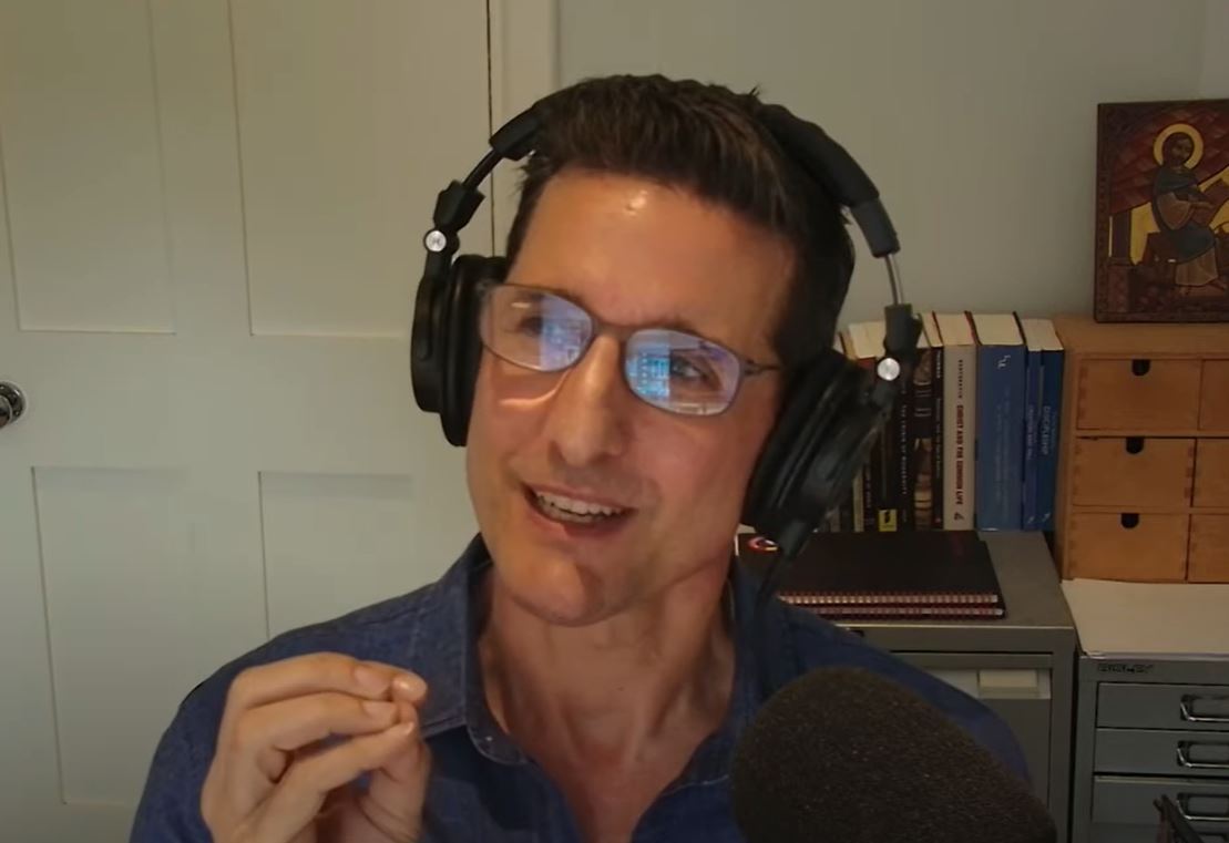 A man talks and gestures with one hand.