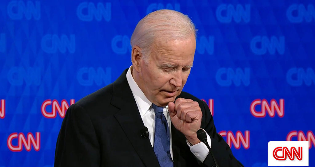 Joe Biden holds a fist to his chest as he stands and speaks.