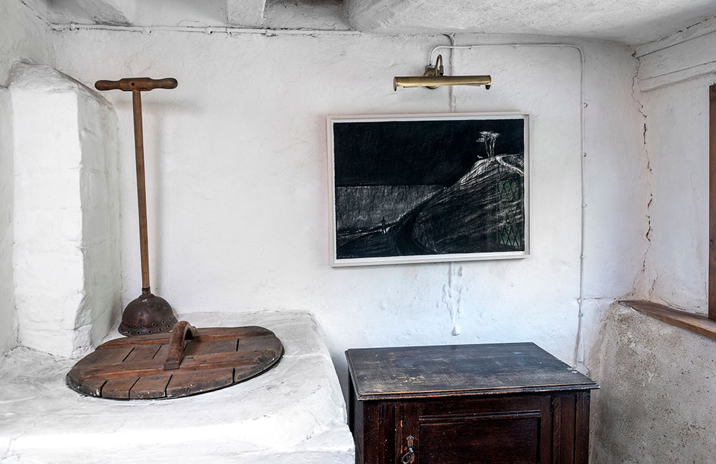 Inside a history cottage, black and white illustrations hang on the wall.
