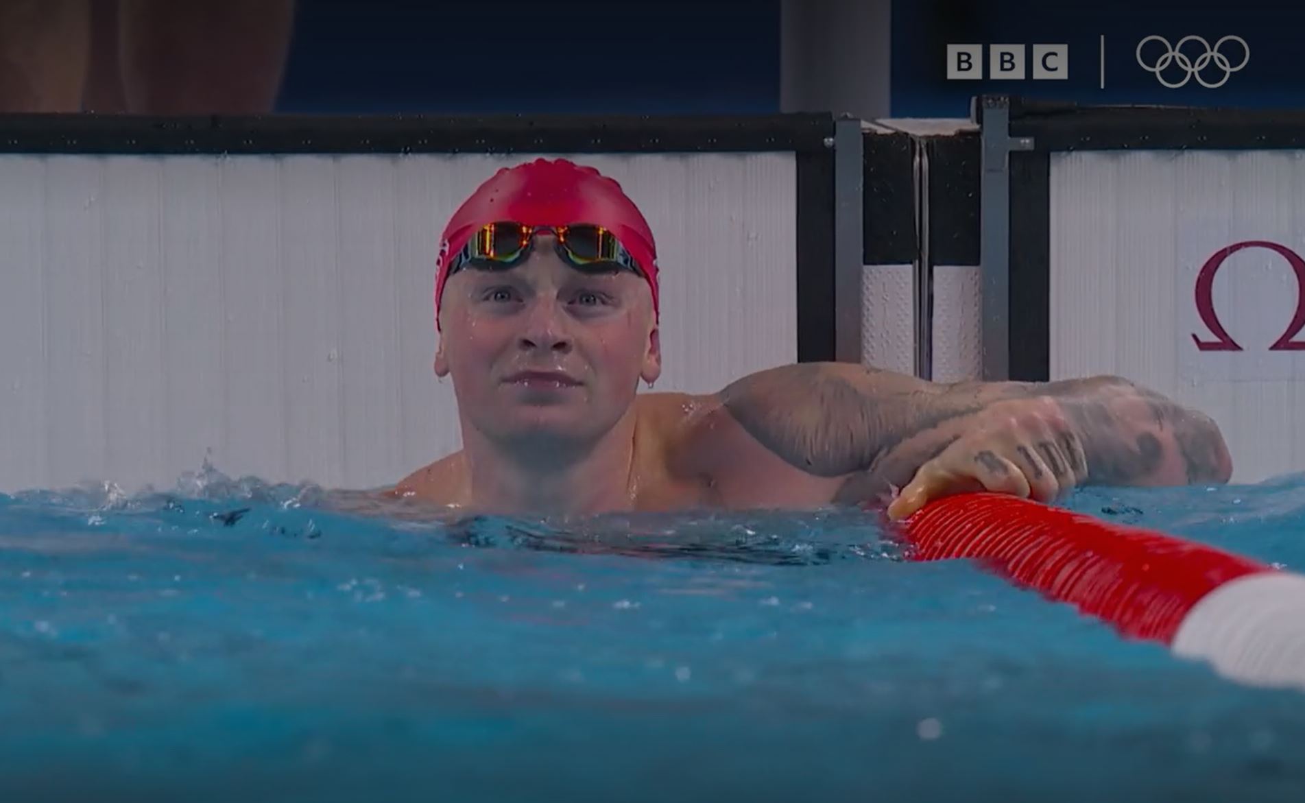 A swimmer at the end of a race, looks to the result screen.