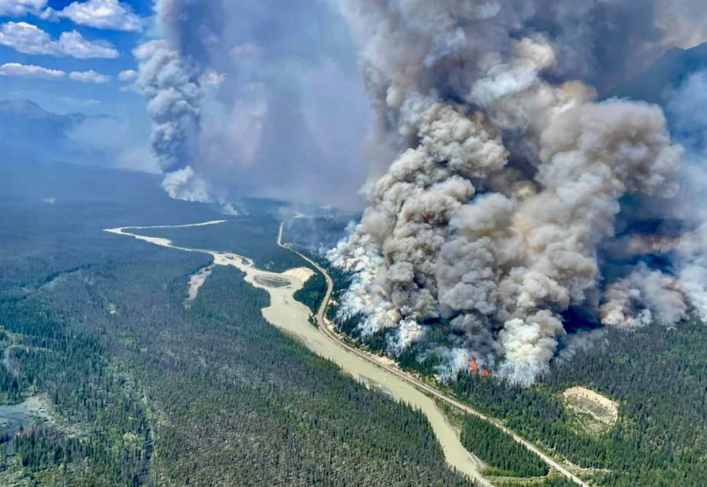 An aerial photography of a huge plume of smoke from a forest fire.