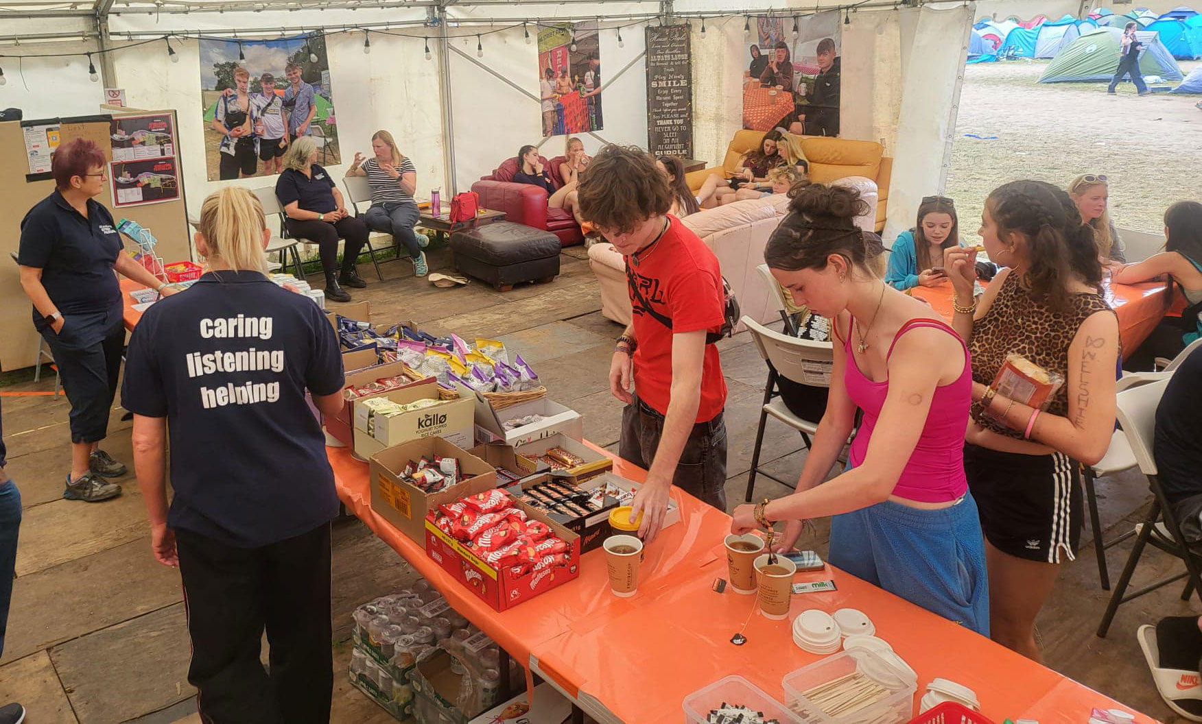 Festival goers, in a cafe tent, make drinks or sit around talking