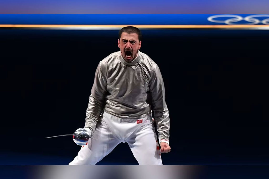 A defeat fencer, withour a mask, turns angrily and roars.