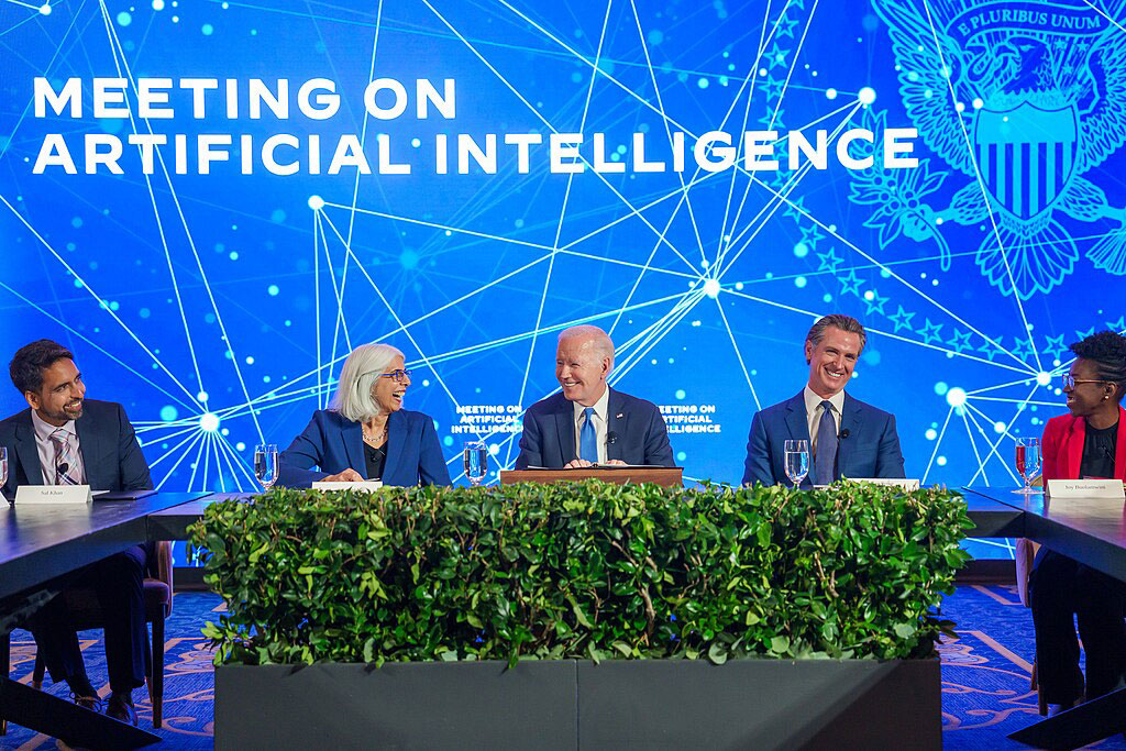 A board of experts sit at a table against a conference backdrop.