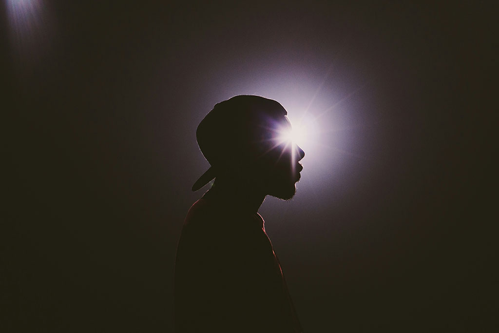 A star burst of light appears to emanate from the eye of a man's head in silhouette. 