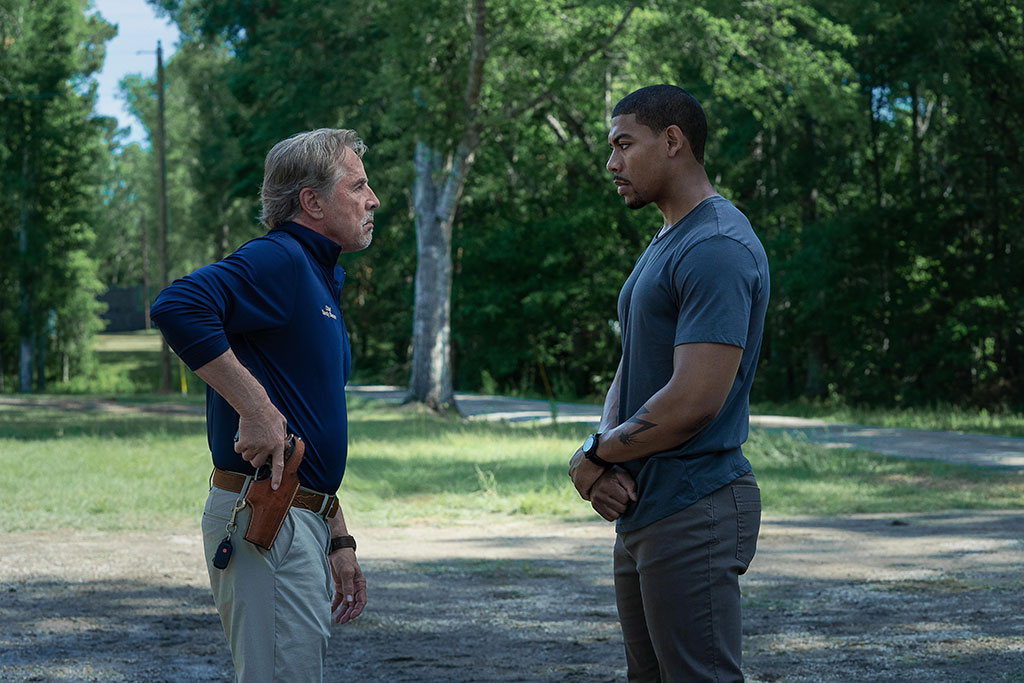 Two men stand off against each other, one holds a holstered gun.