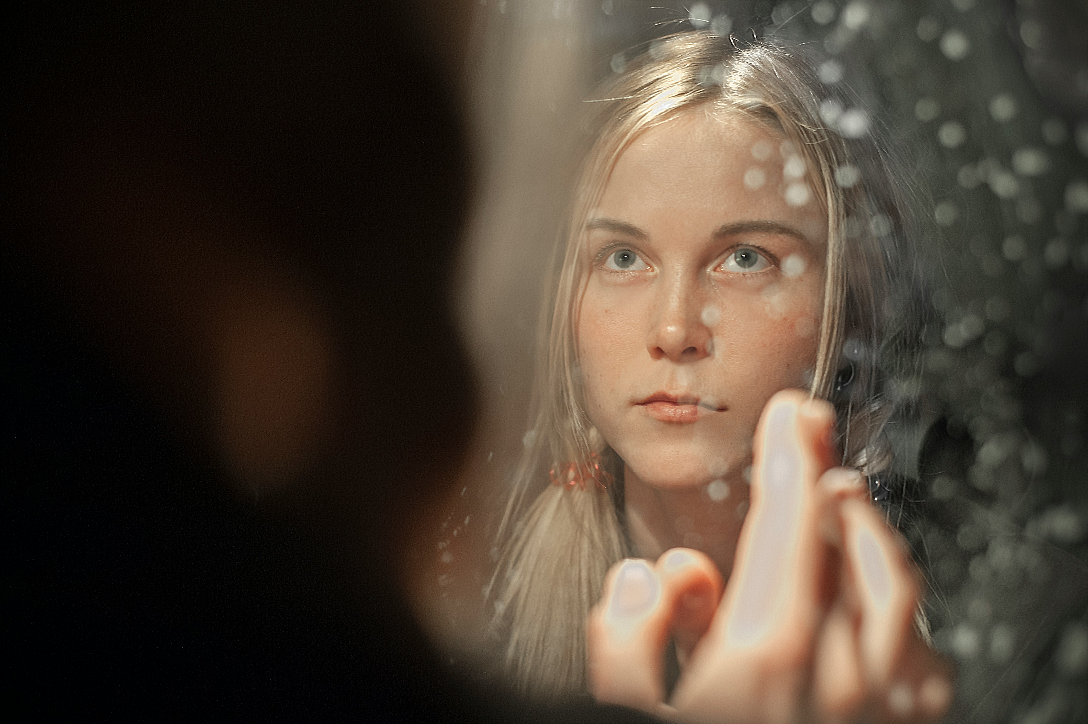 A woman sees her reflection in a mirror and hold a finger up.