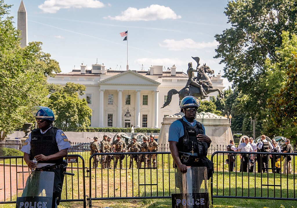 Riot police stand guard outside a White House fence line. 