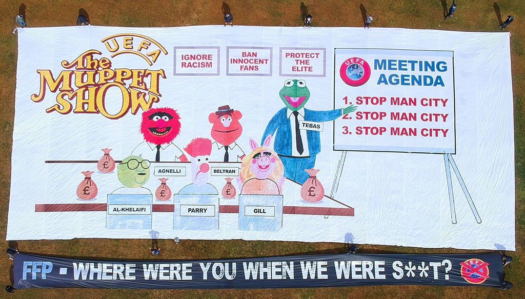 A football support protest banner depicts The Muppet Show logo, a meeting of men in suits and various slogans.