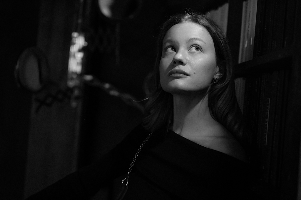 A black and white picture shows a woman head and shoulders, she is looking up and to the side in an unsure way.