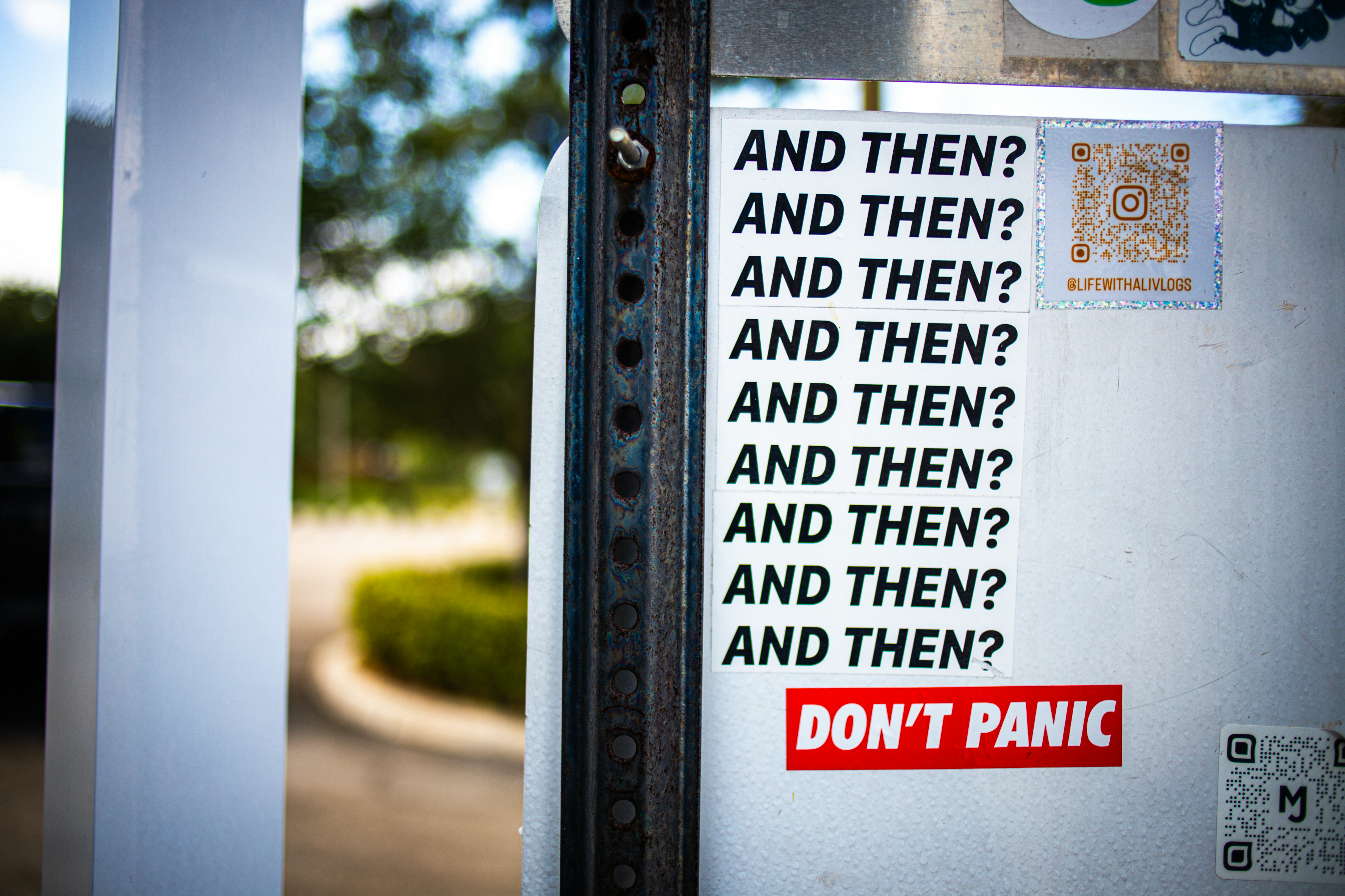 A street sticker displays multiple lines reading 'and then?'