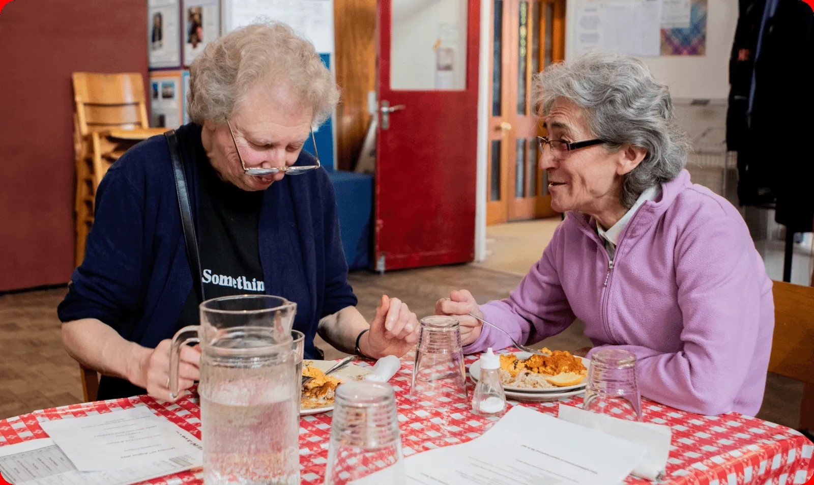 two women sit a table chatting.