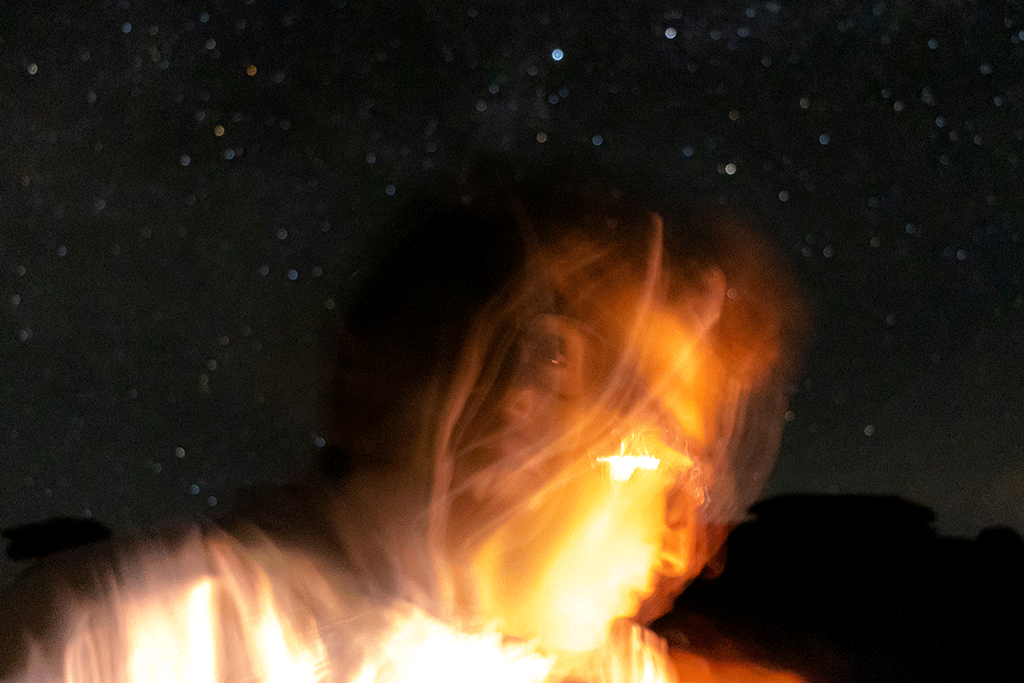Against a night sky a lit up face is blurred by the camera movement.