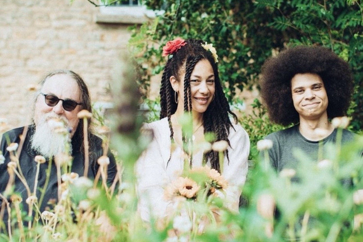 three folk musicians face the camera across a meadow