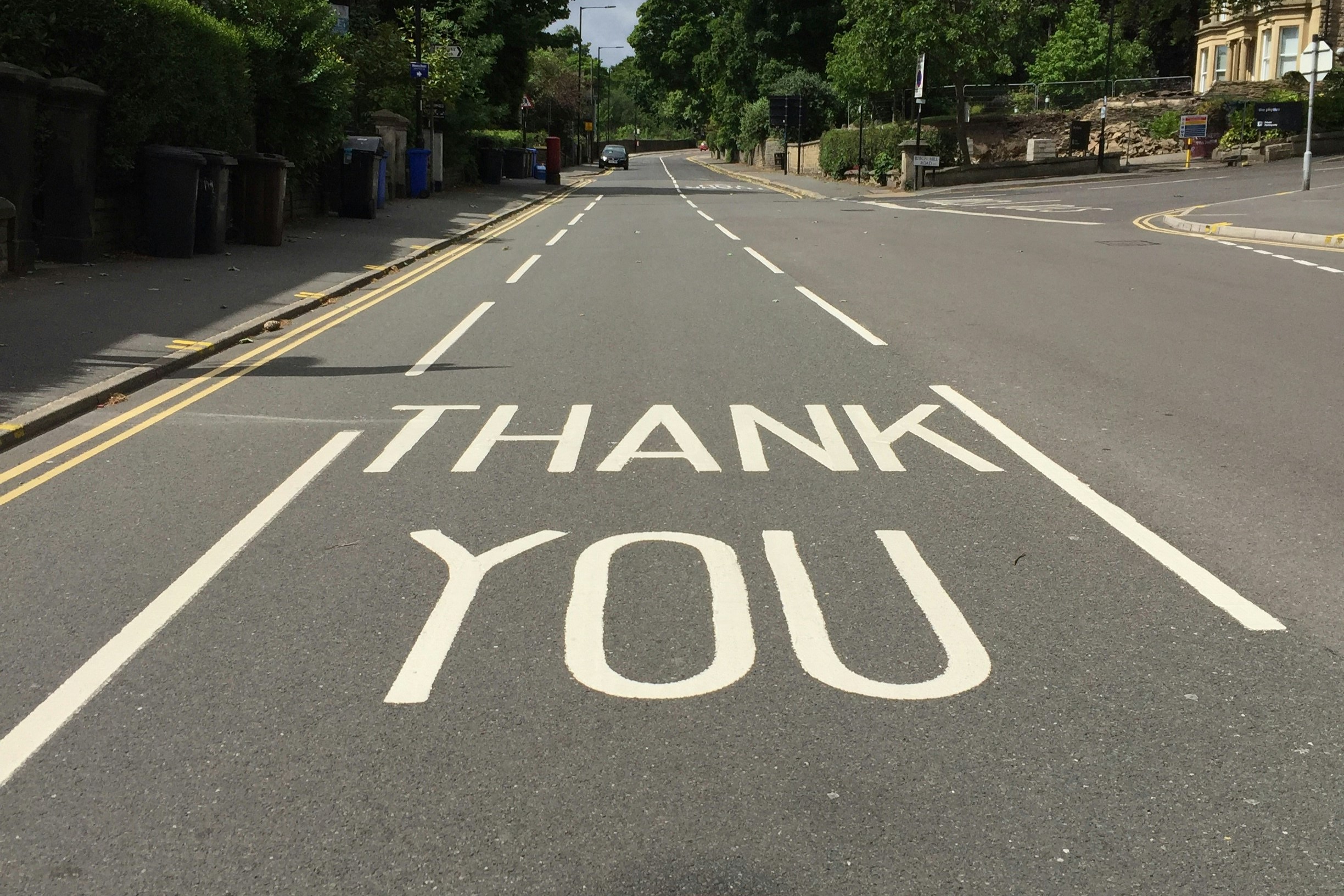 A  painted sign on a road reads 'THANK YOU'