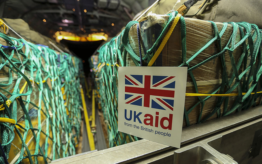 Cargo sits in nets inside a plane, a sign reads 'UK Aid'