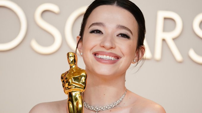 Mikey Madison, wearing a ball gown, clutches a golden Oscar statue.