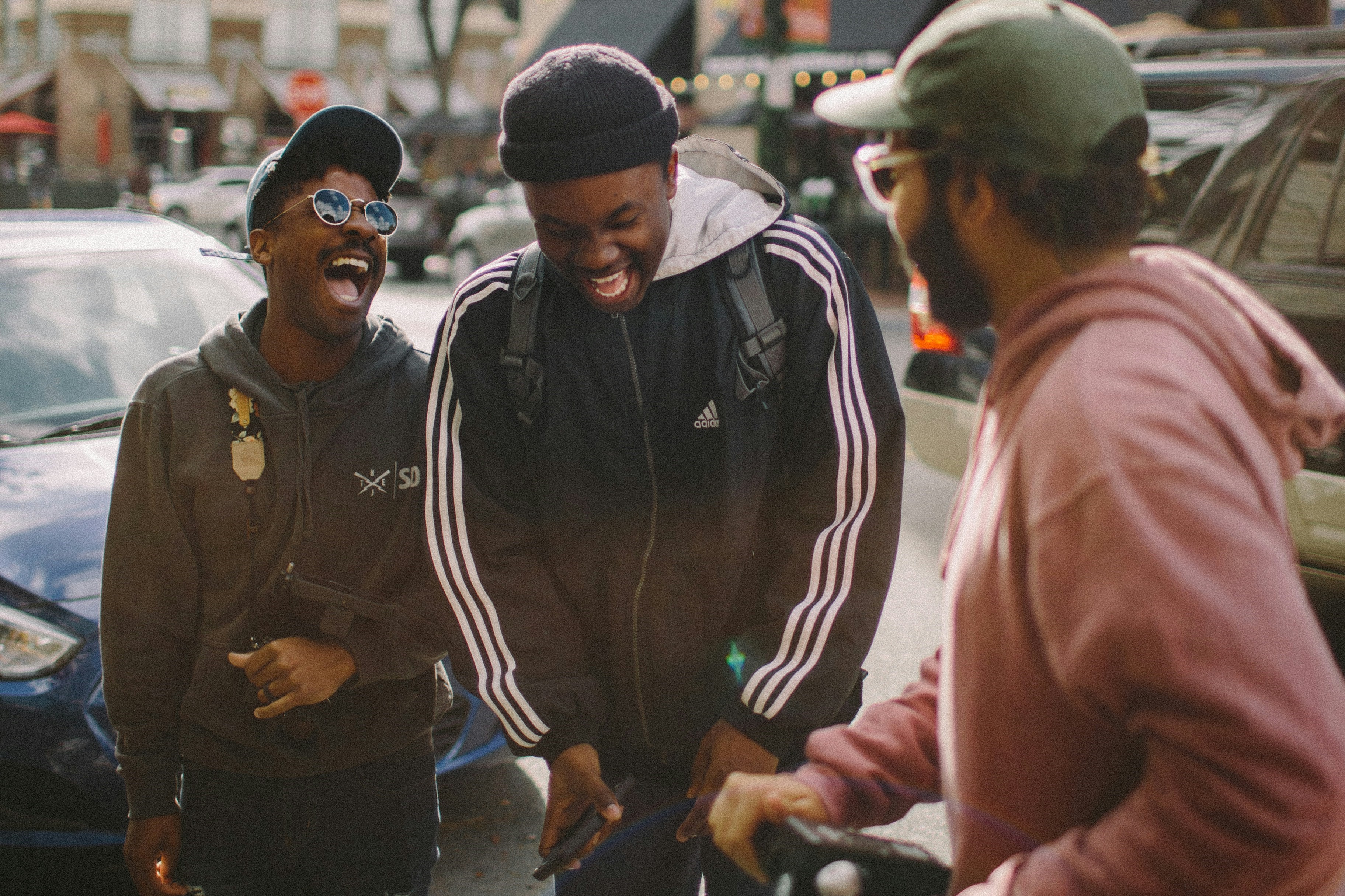 Three friends in the street laugh together.
