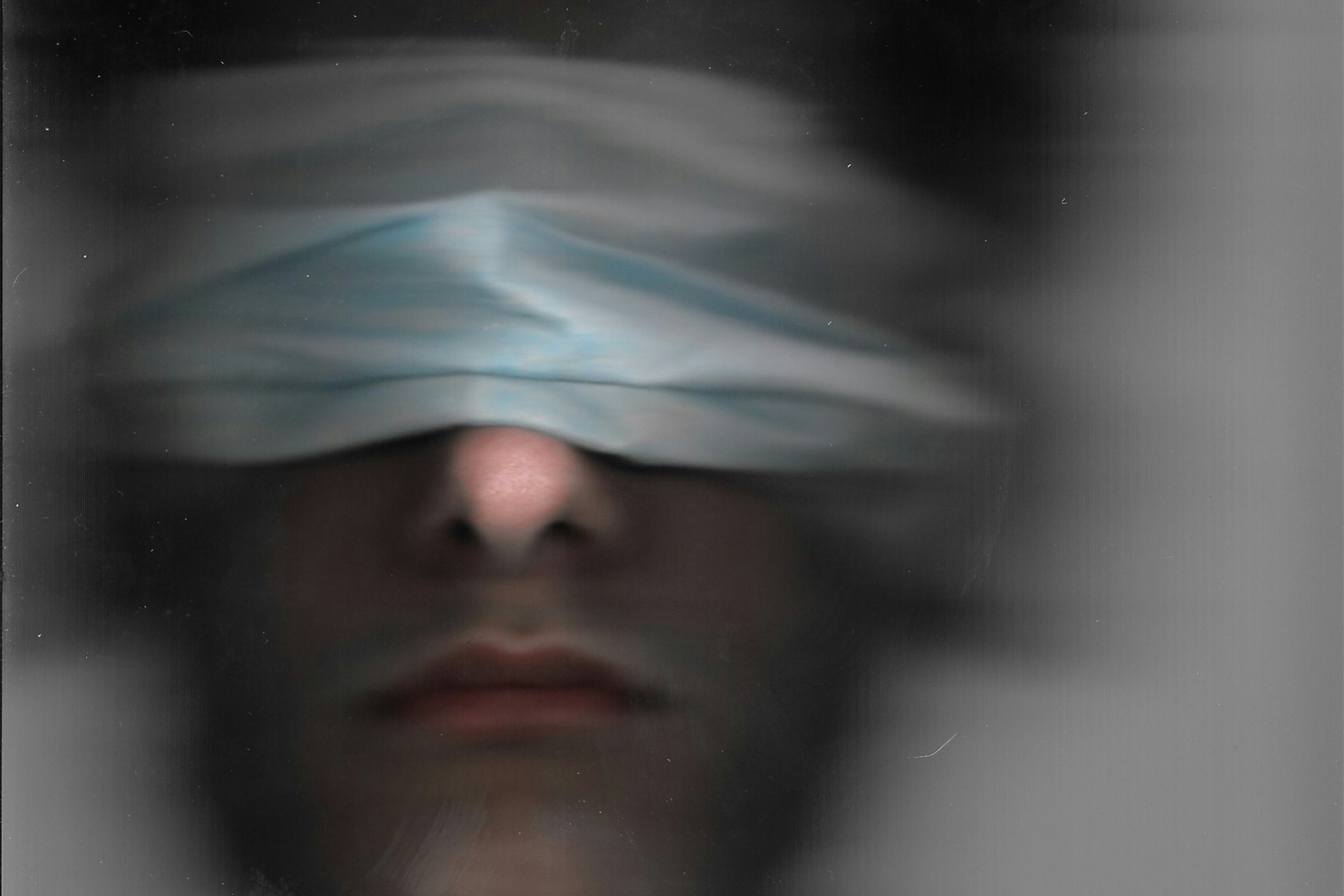 A blurred image of a blindfolded man.