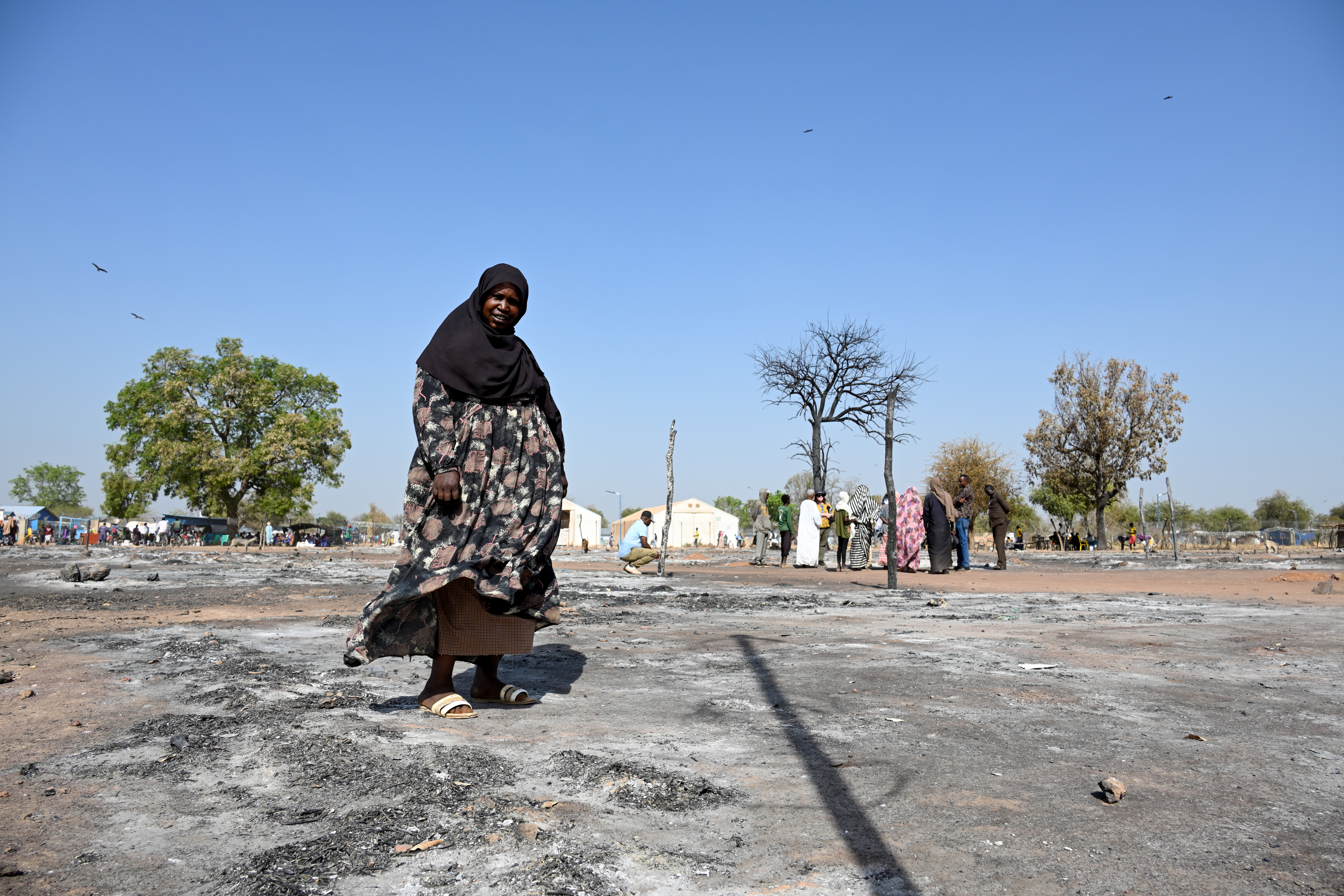 A Sudanese woman walks across the ashes of a burnt out street market.