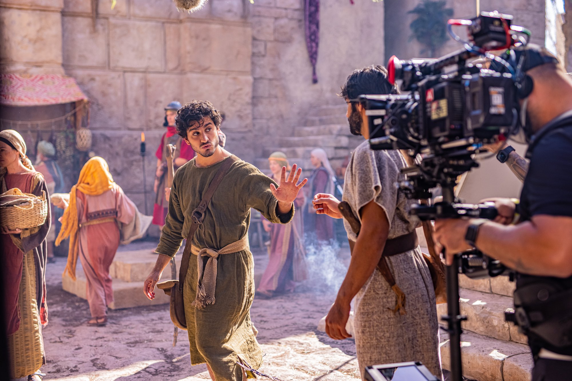 An actor dressed in an ancient Middle Eastern way is filmed by a large camera.