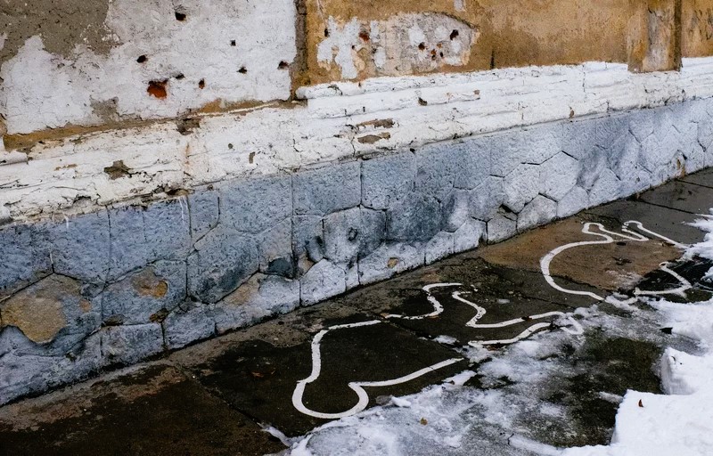 Bullet holes on a wall and white paint outlines mark the site of an execution