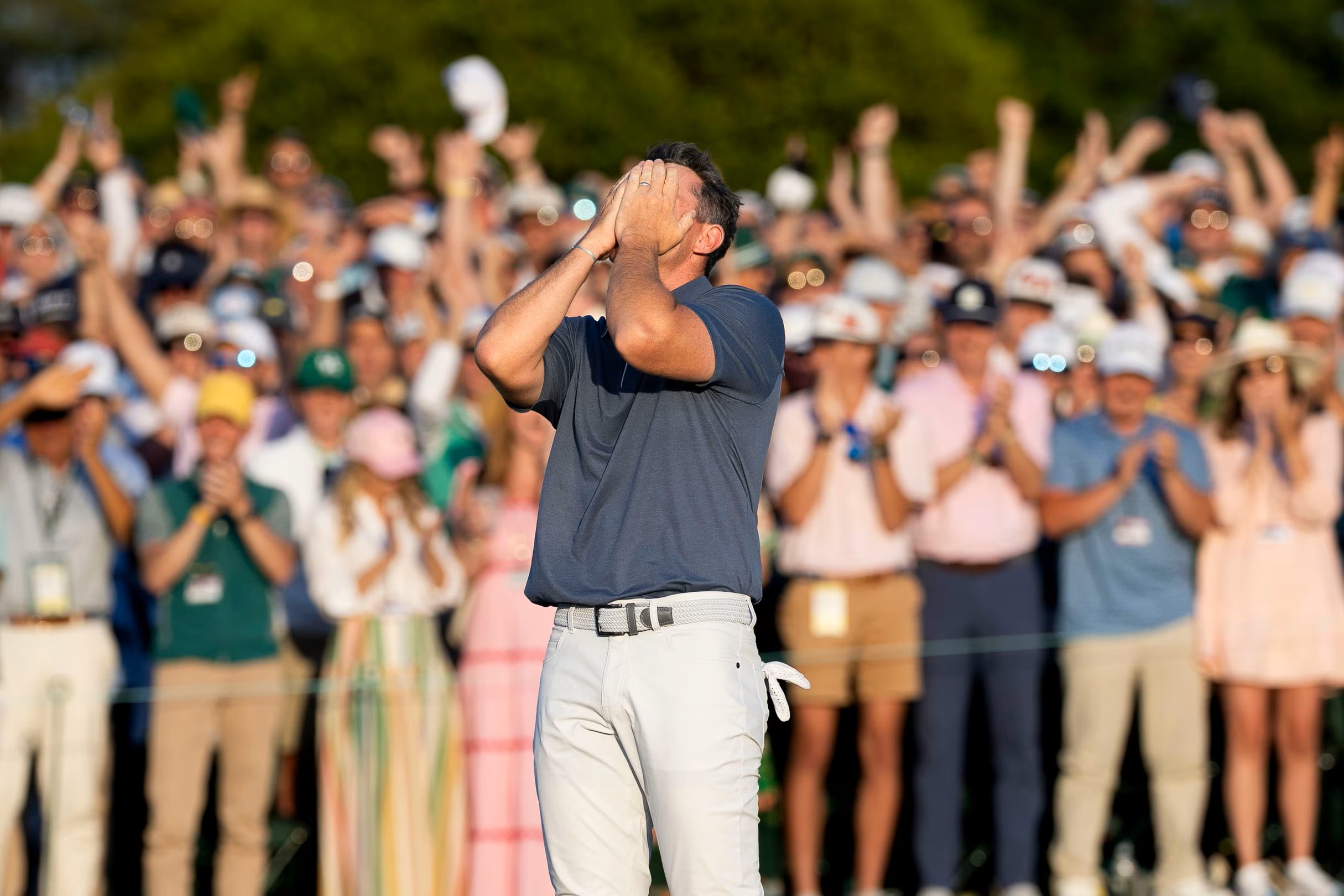 A golf clutches his face after winning a competition