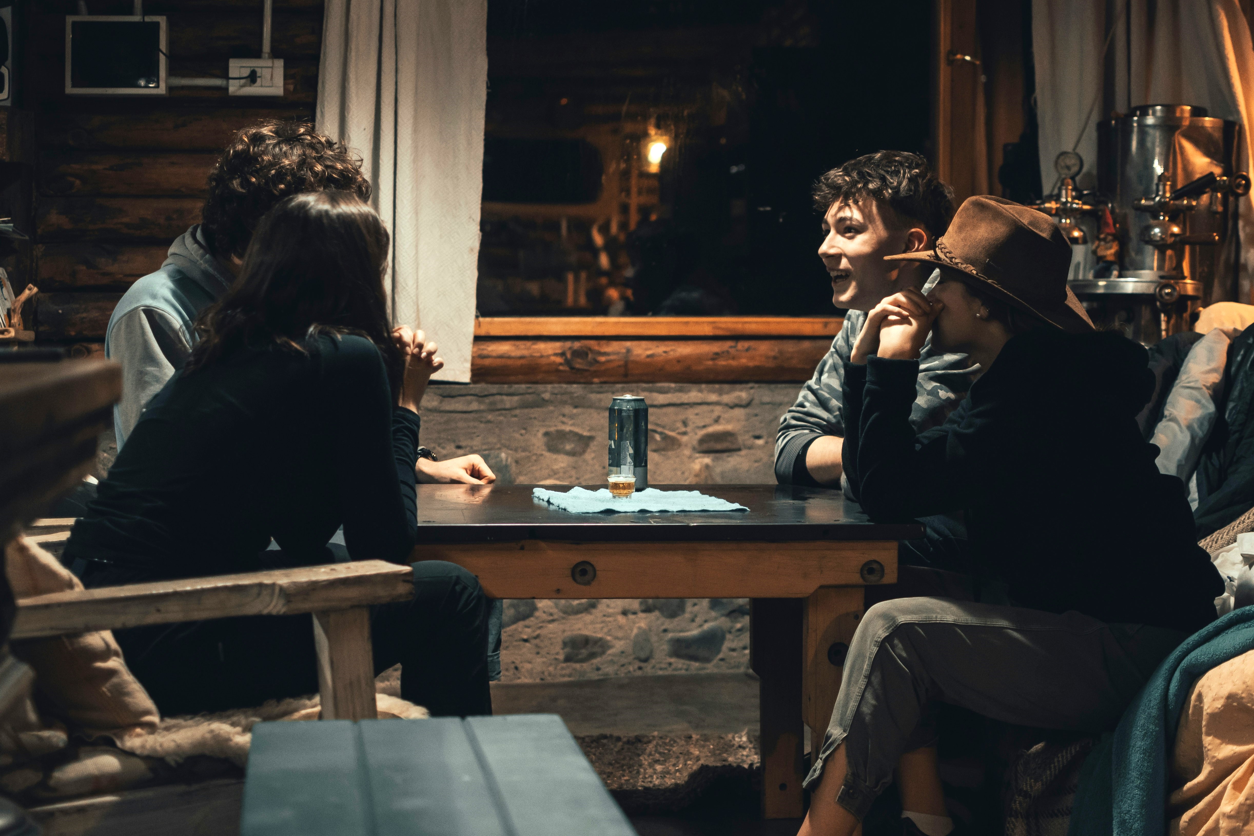 Four people sit round a pub table, some look animated, others pensive.