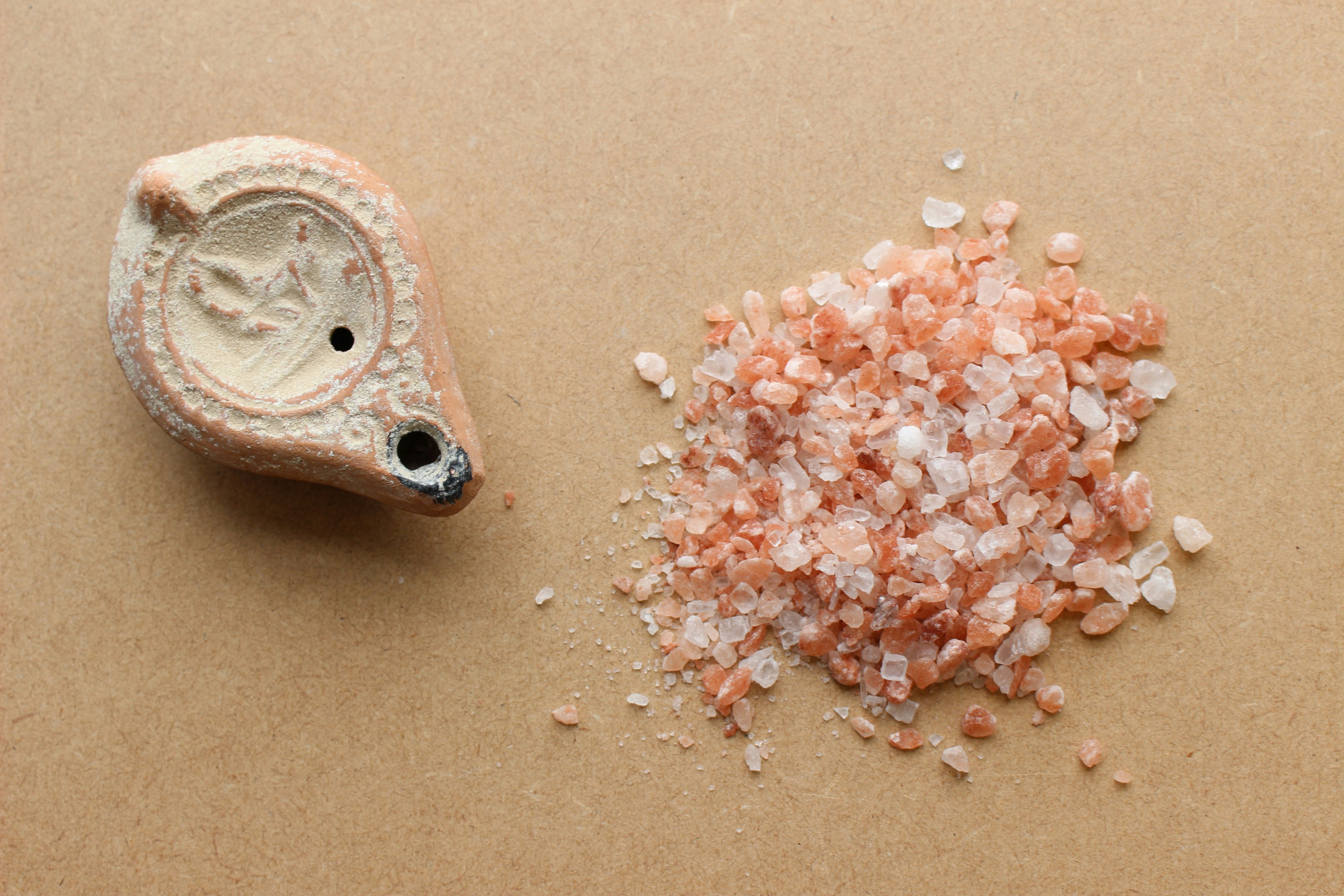 An ancient salt shaker sits next to a pile of crushed rock salt.