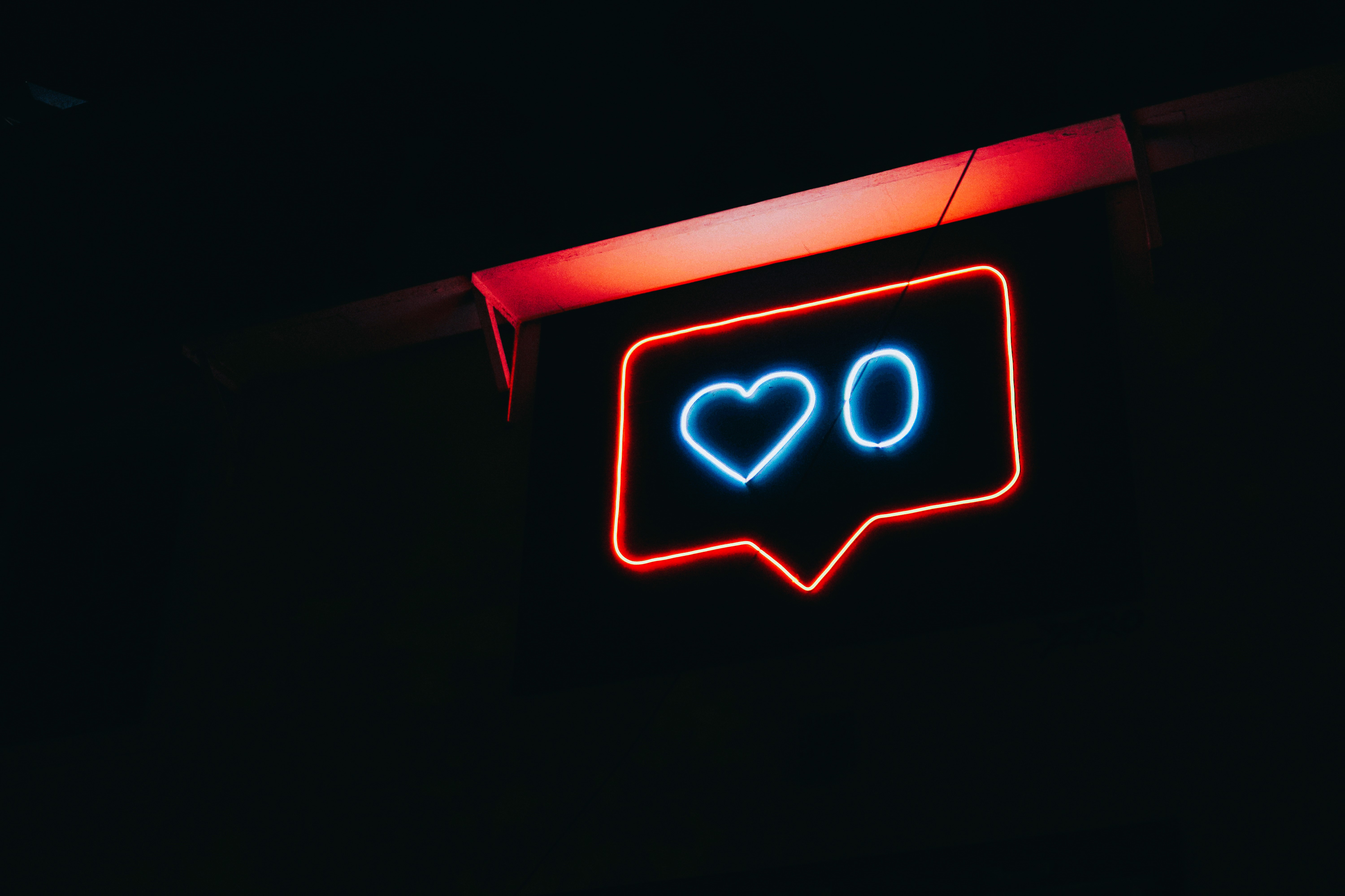 A neon sign depicts a message balloon with a heart symbol and a zero next to it.