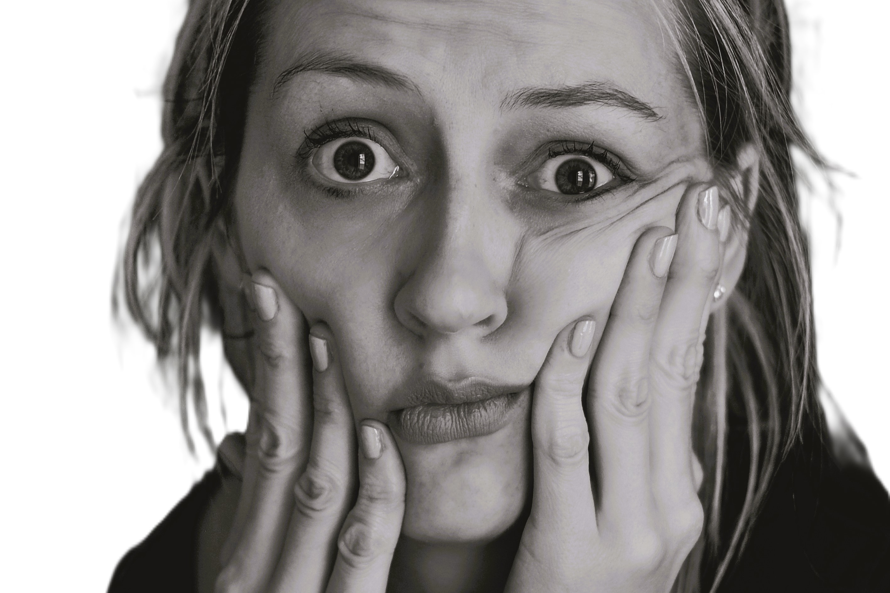 A perplexed looking woman hold her cheeks up with her fingers.