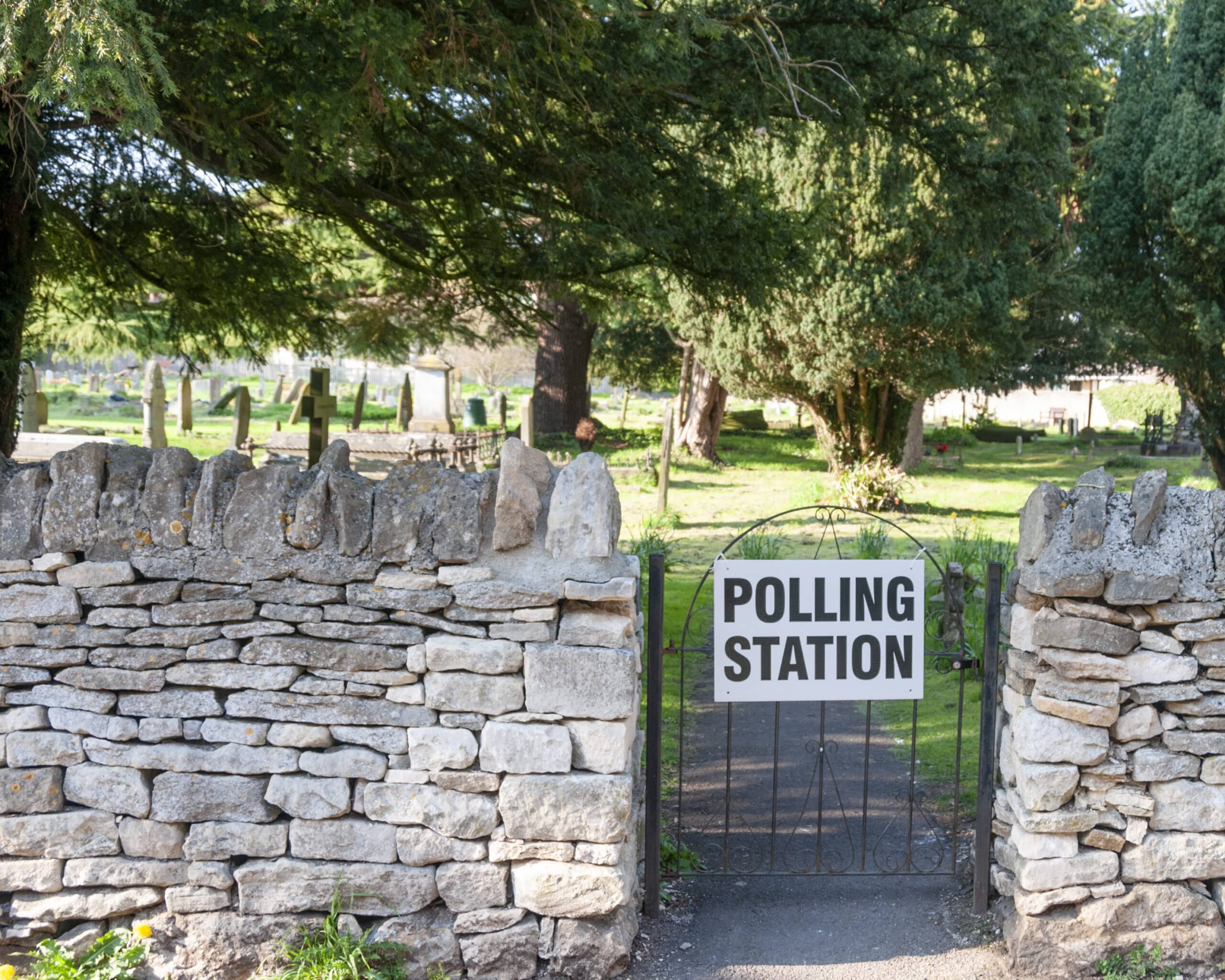 A gate to a churchyard displays a sign saying polling station.