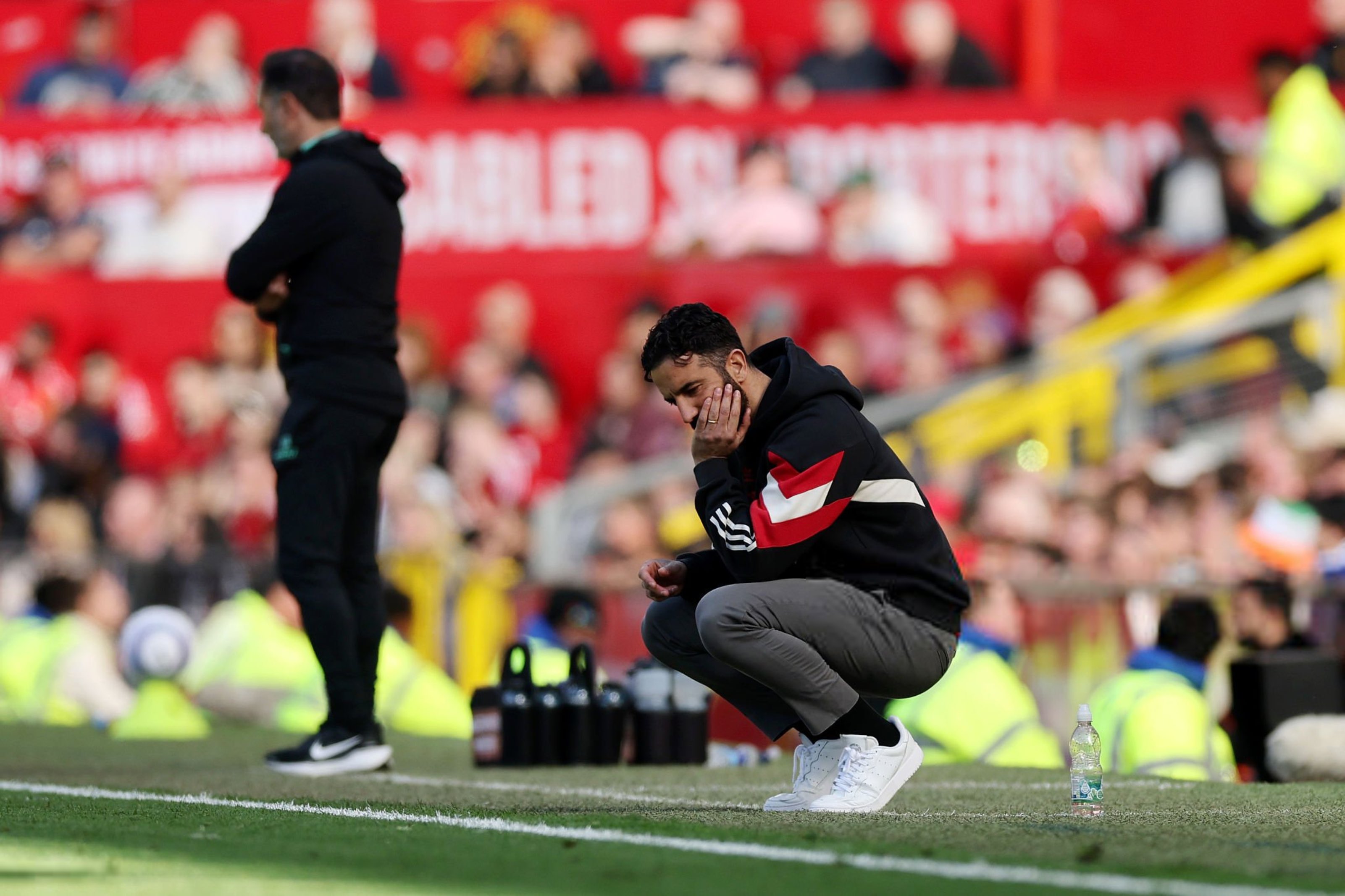 A dejected football coach squats by the byline.