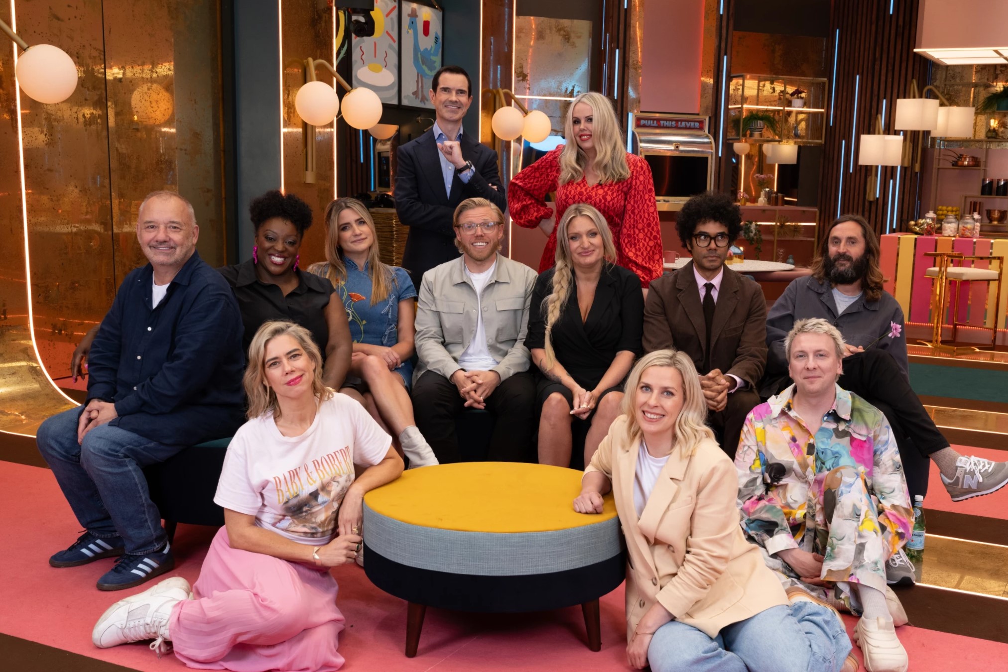 A group of comedians pose on a TV show set.