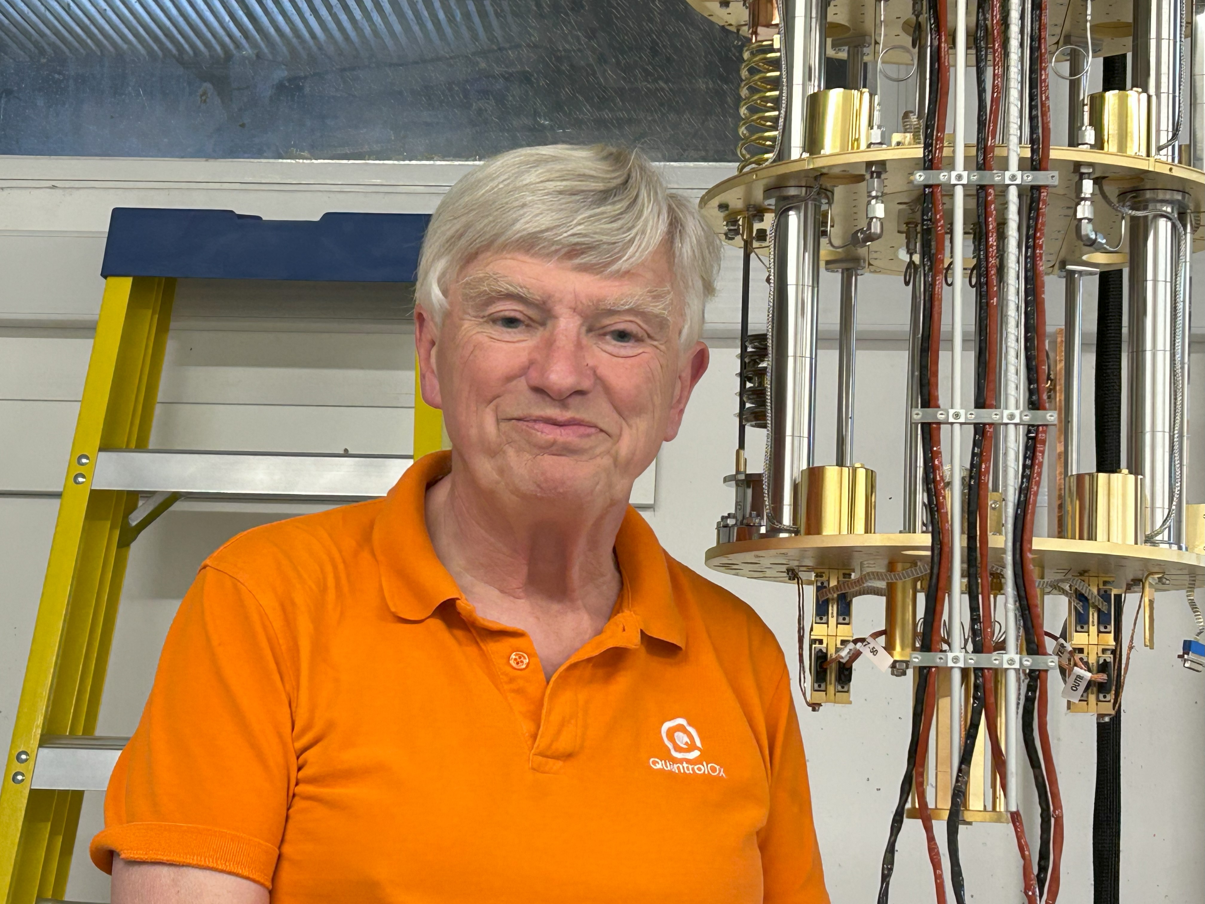 A professor stands next to experimental equipment.