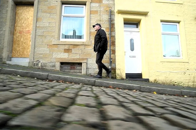 A man walks up a cobble street.