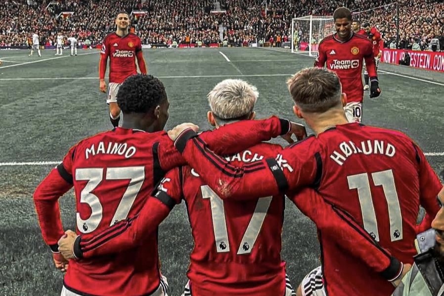 Three Manchester United footballers with their arms around each others backs.