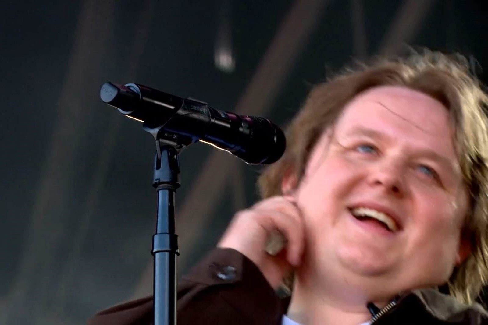 A singer leans back from the mic smiling