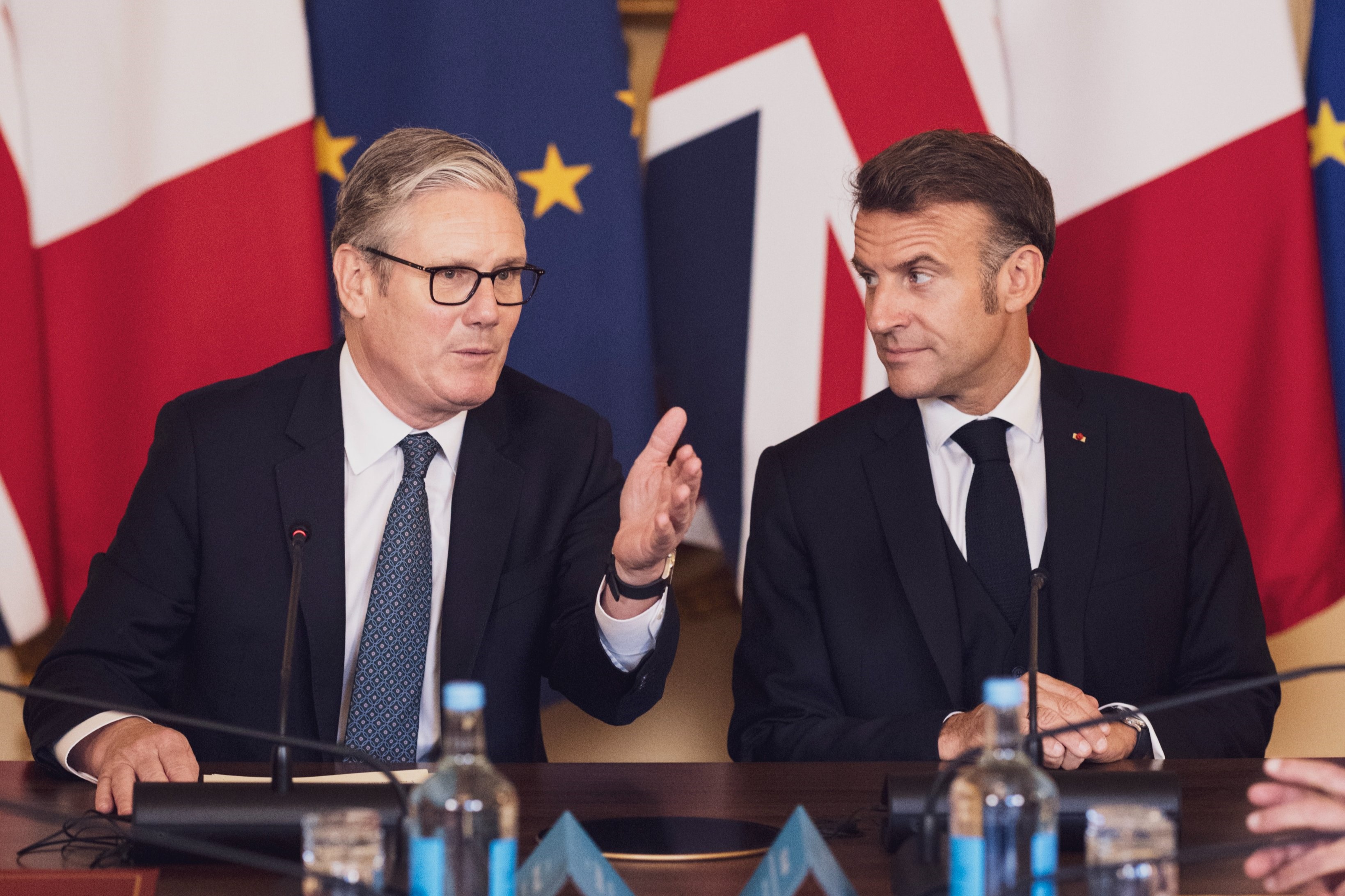 Keir Starmer and Emmanuel Macron in front of flags.
