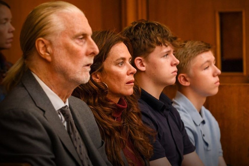 A family sit together watching a trial in a court.