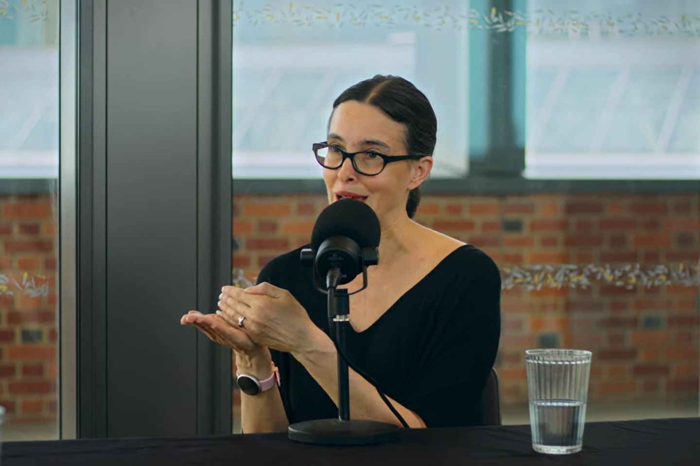 a woman speaks and gestures while recording a podcast
