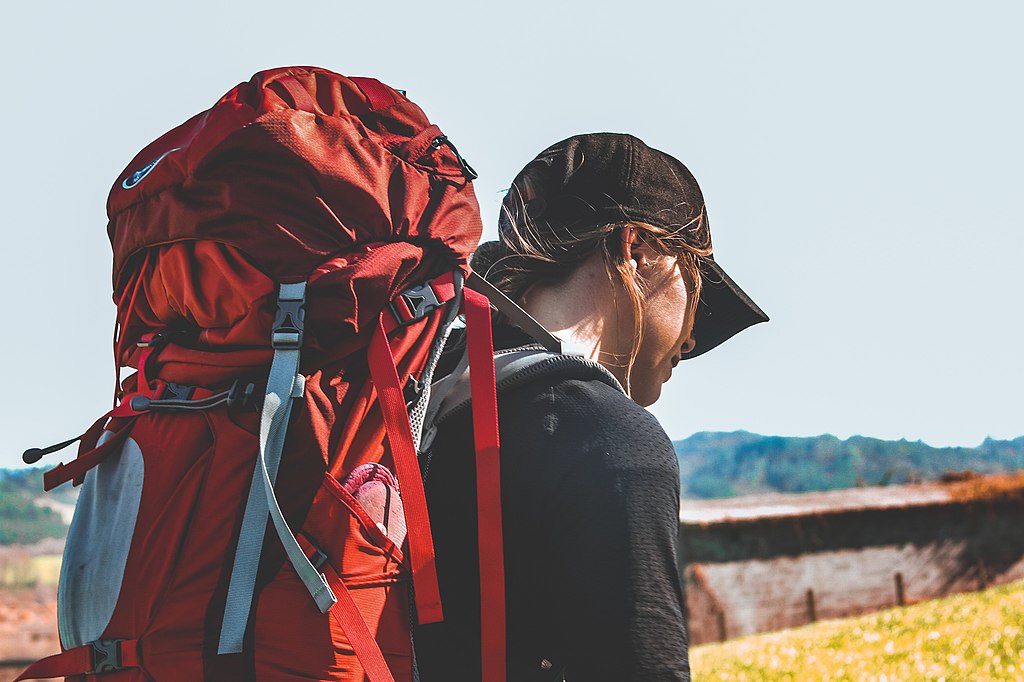 A pilgrim with a red backpack heads off.