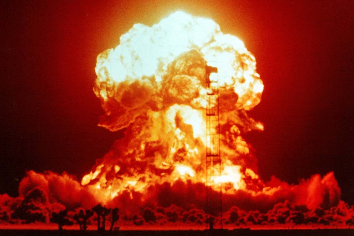 A nuclear explosion glows red and orange against the night sky.