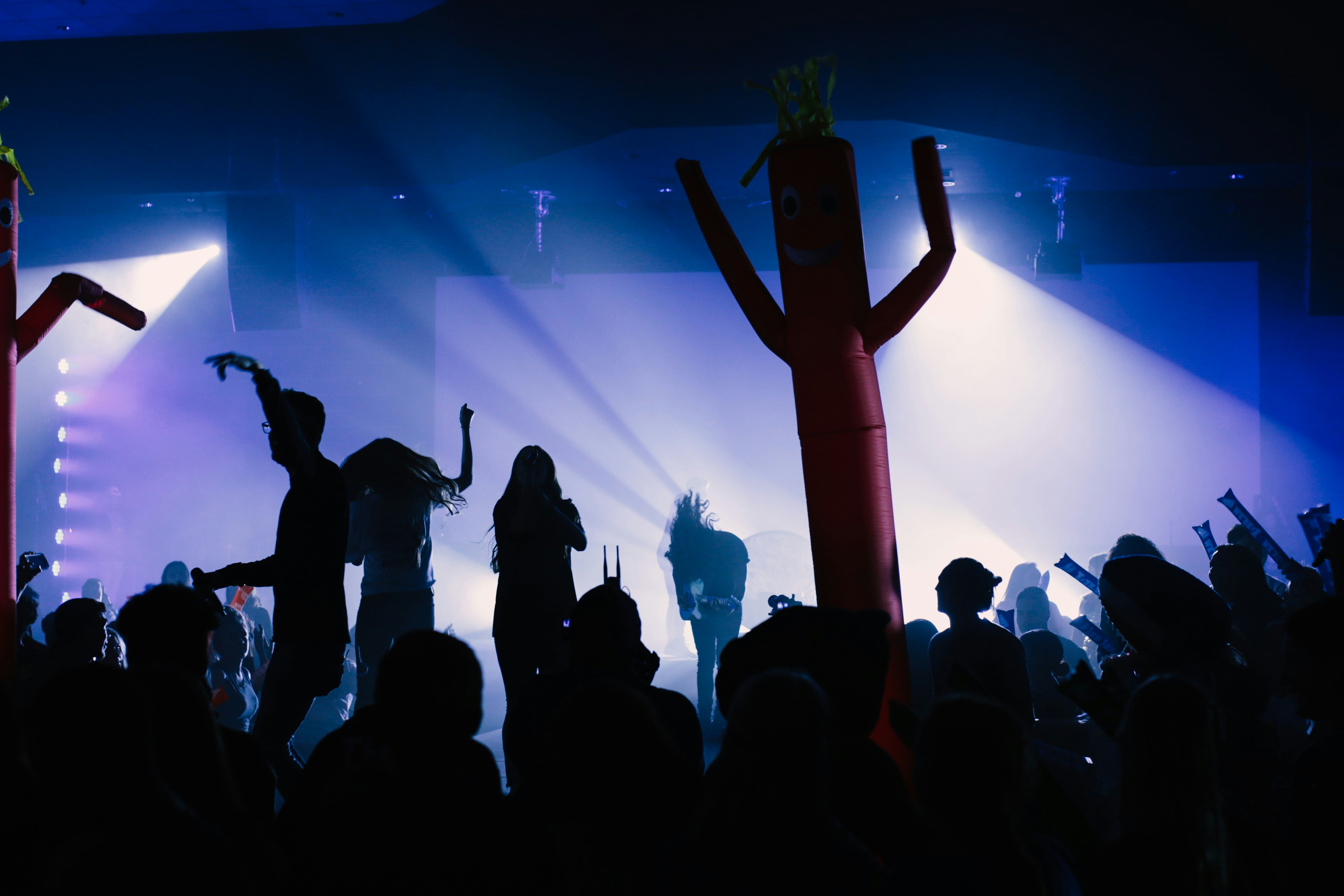 A band and audience are back lit against a stage.