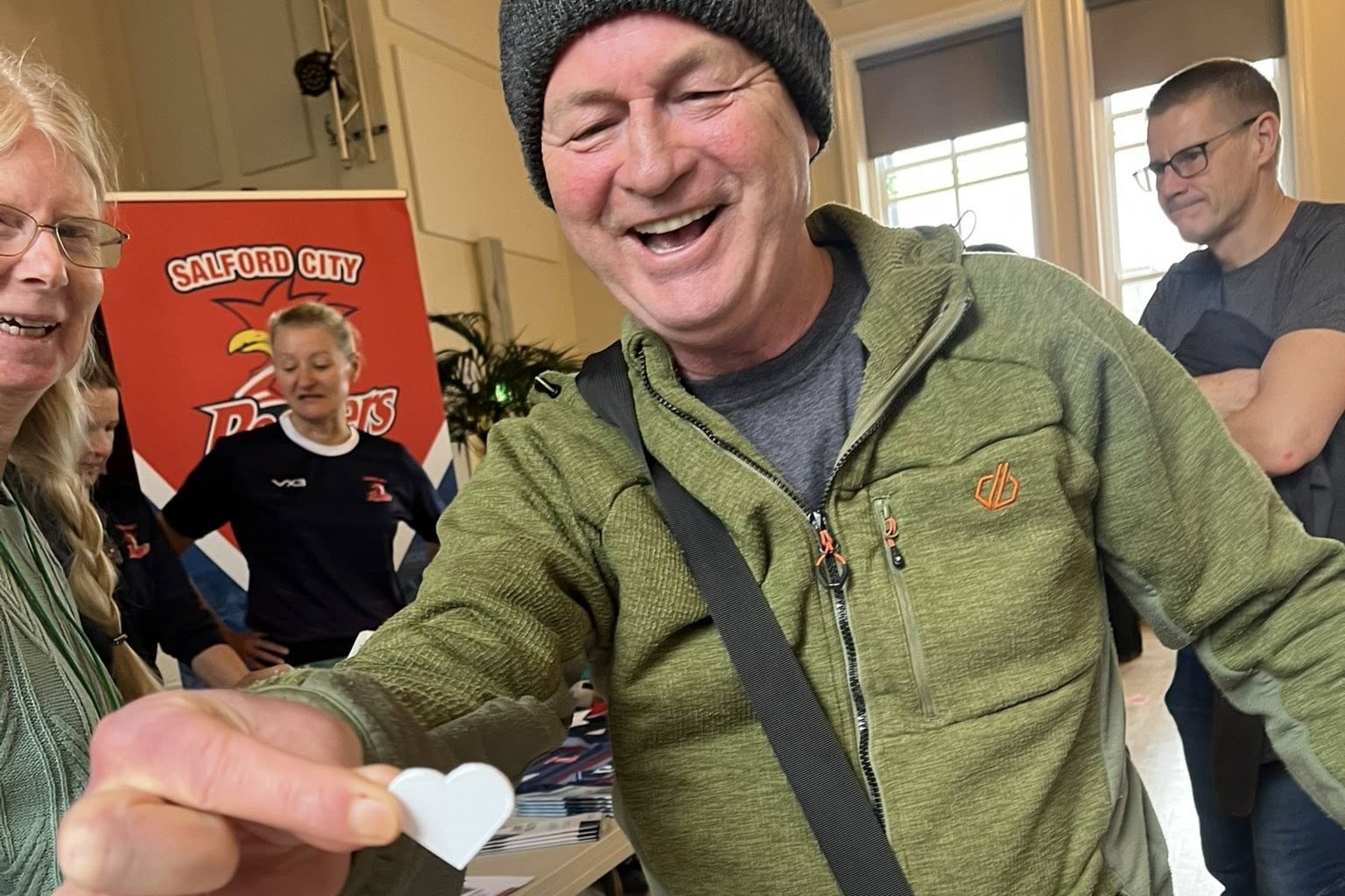 A man presents a heart shaped paper token towards the camera