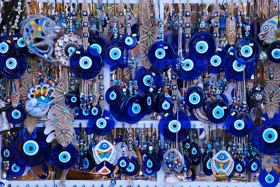 Blue evil eye charms hang among a jewellery display